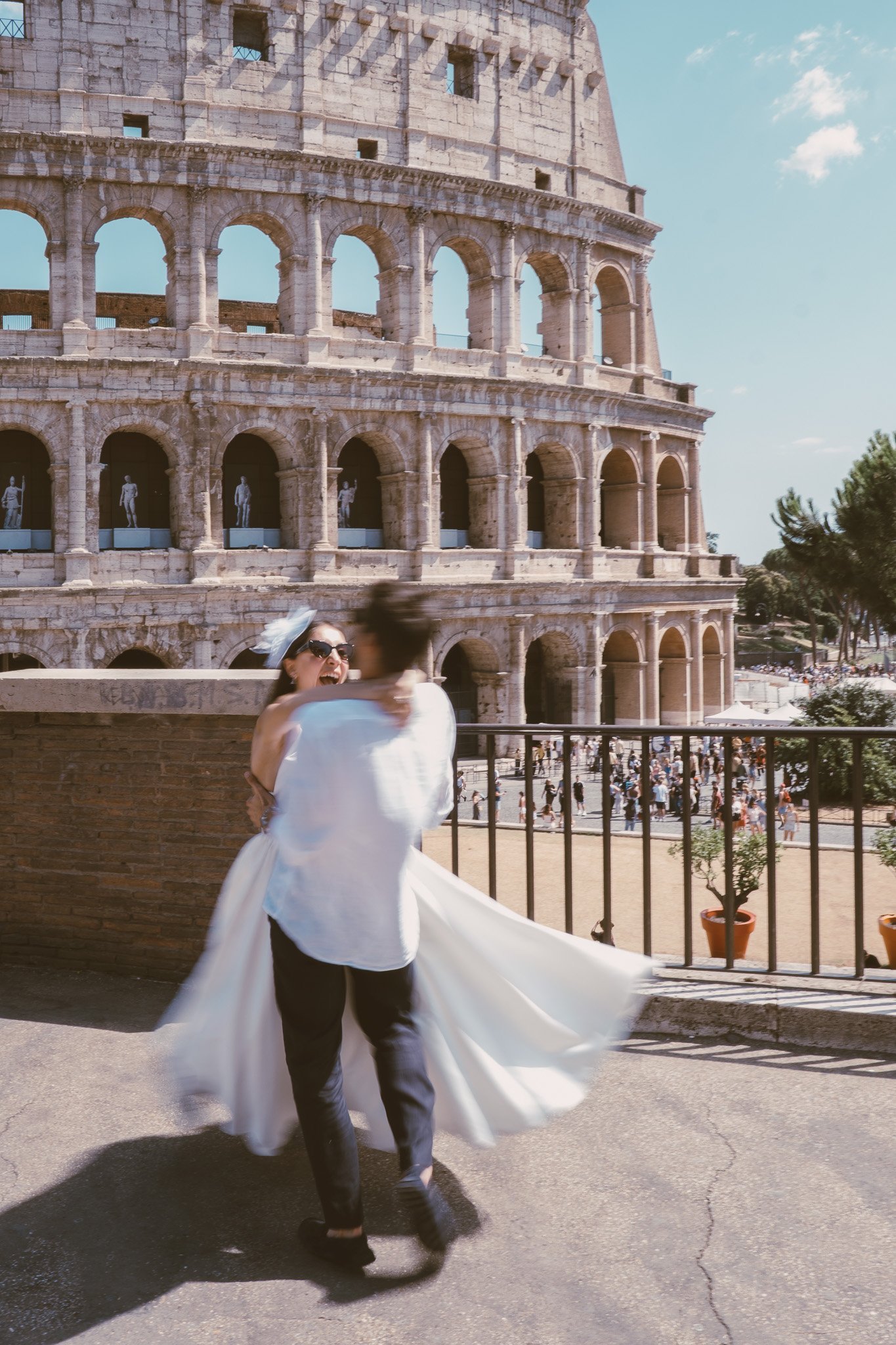Coppia di sposi che balla davanti al Colosseo a Roma durante un servizio fotografico di matrimonio romantico.