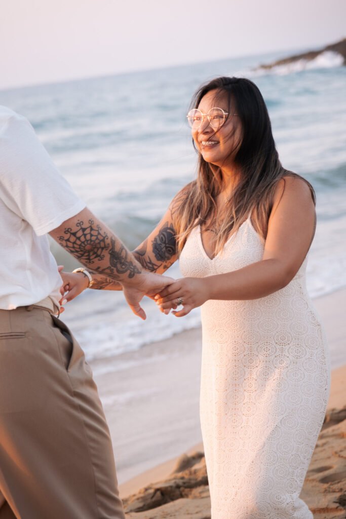 Donna sorridente che cammina mano nella mano con il partner sulla spiaggia.