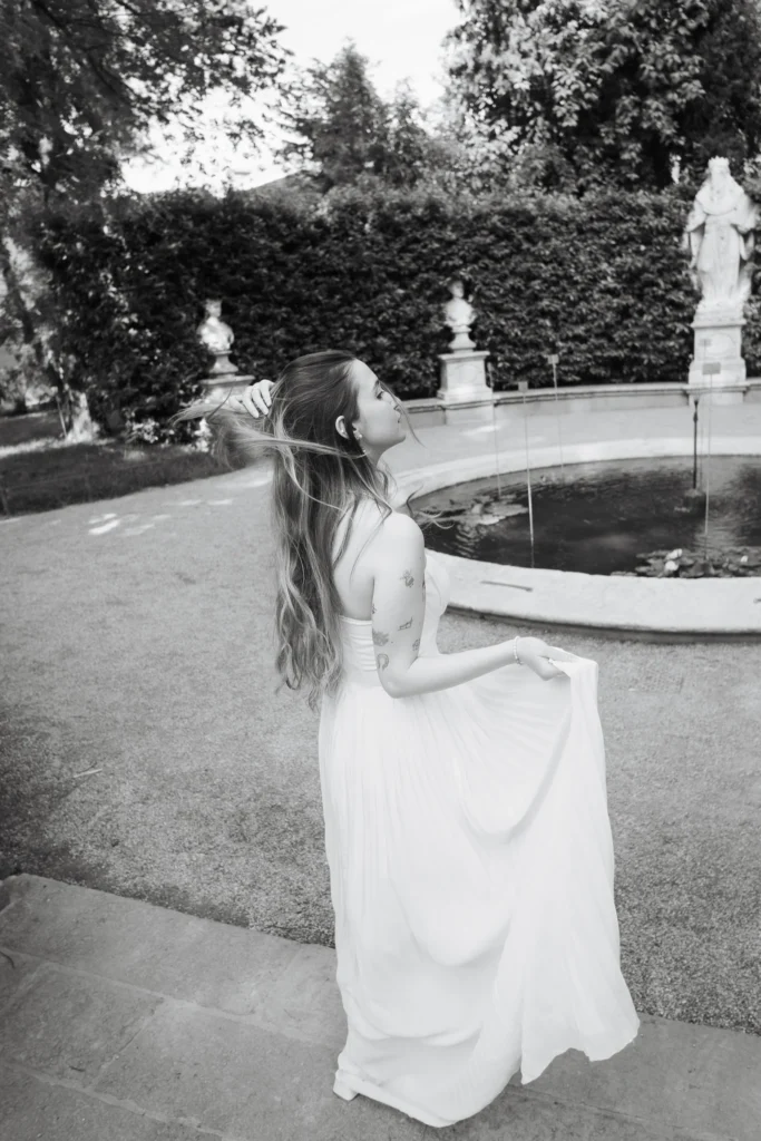 Capturing Love in Timeless Frames: The Art of Editorial Wedding Photography in Italy 1 Bride in flowing white dress standing near a fountain in an Italian garden.