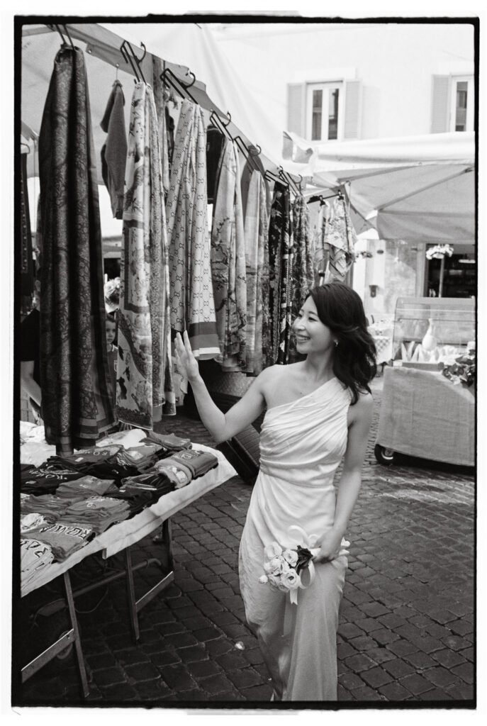 Pre Wedding Photoshoot in Rome with Natsuki and John 1 Bride smiling while looking at fabrics in a Roman street market during her pre wedding photoshoot in Rome.