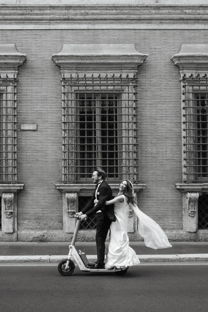 Sposi in monopattino durante un servizio fotografico di matrimonio elopement a Roma, in bianco e nero.