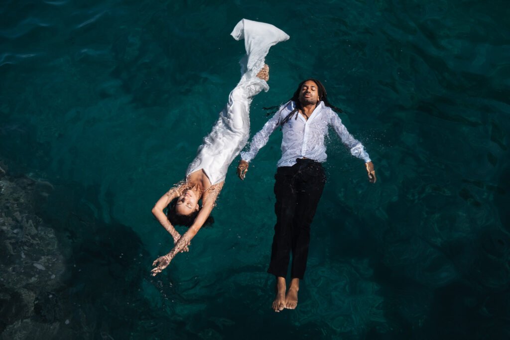 Gli sposi Désirée e Matthew che galleggiano insieme nel mare di Sicilia dopo la cerimonia — fotografia di matrimonio in Sicilia di Gökhan Kutluer.