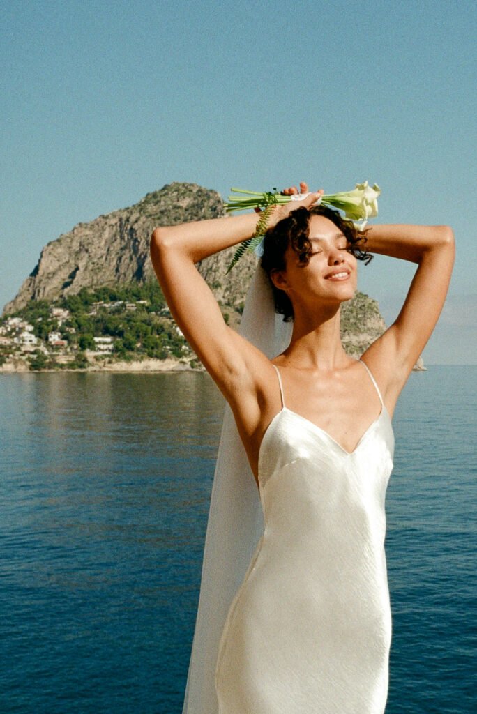 Cinematic wedding portrait in Italy of a bride by the sea, photographed on 35mm film with soft Mediterranean light and natural elegance.