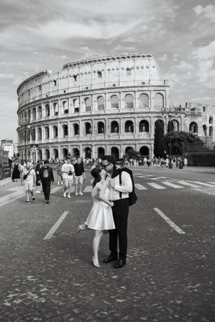 Black and white photo of a couple kissing in front of the Colosseum in Rome, captured with a cinematic wedding photography style.