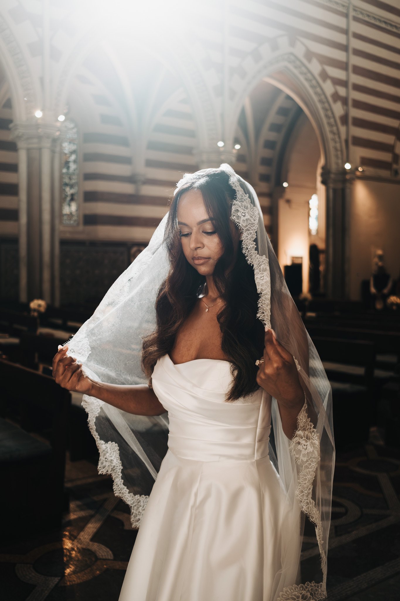 Sposa con velo in pizzo all’interno della Chiesa di San Paolo entro le Mura durante un micro wedding intimo a Roma, fotografata con luce naturale e ombre morbide.