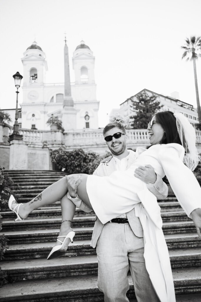Black and white joyful pre wedding portrait of Vivian and Hamish laughing together at the Spanish Steps in Rome during a couple photoshoot in Italy.