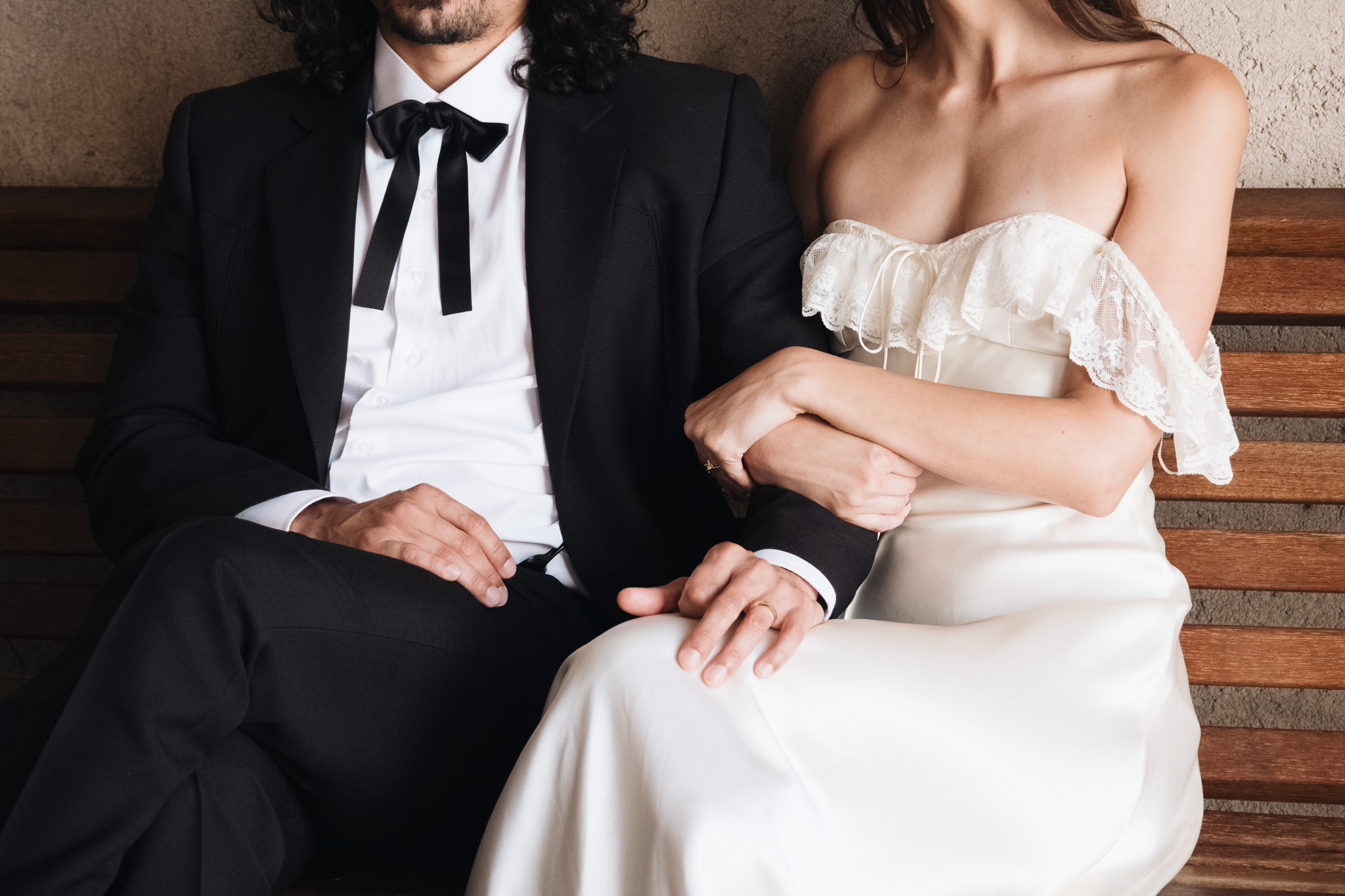Dettaglio elegante degli sposi seduti su una panchina durante un matrimonio intimo a Spello, in Umbria.