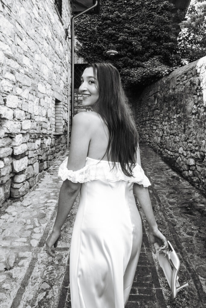 Bride smiling while walking through a narrow stone street in Spello during her intimate elopement in Umbria.