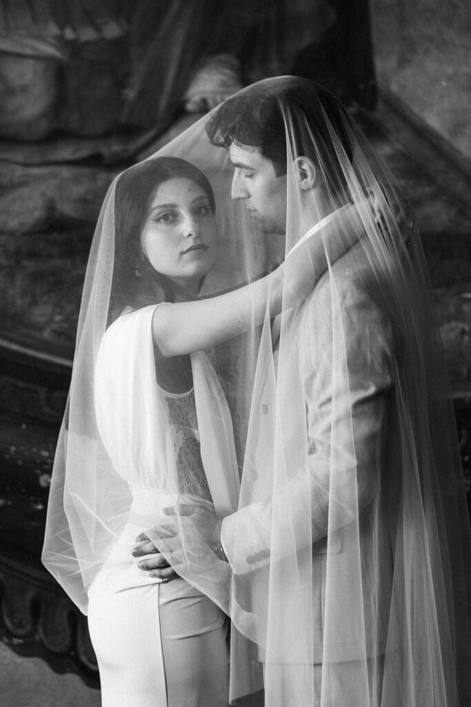 Bride and groom standing under a wedding veil inside Comune di Tivoli during an intimate civil wedding in Italy.