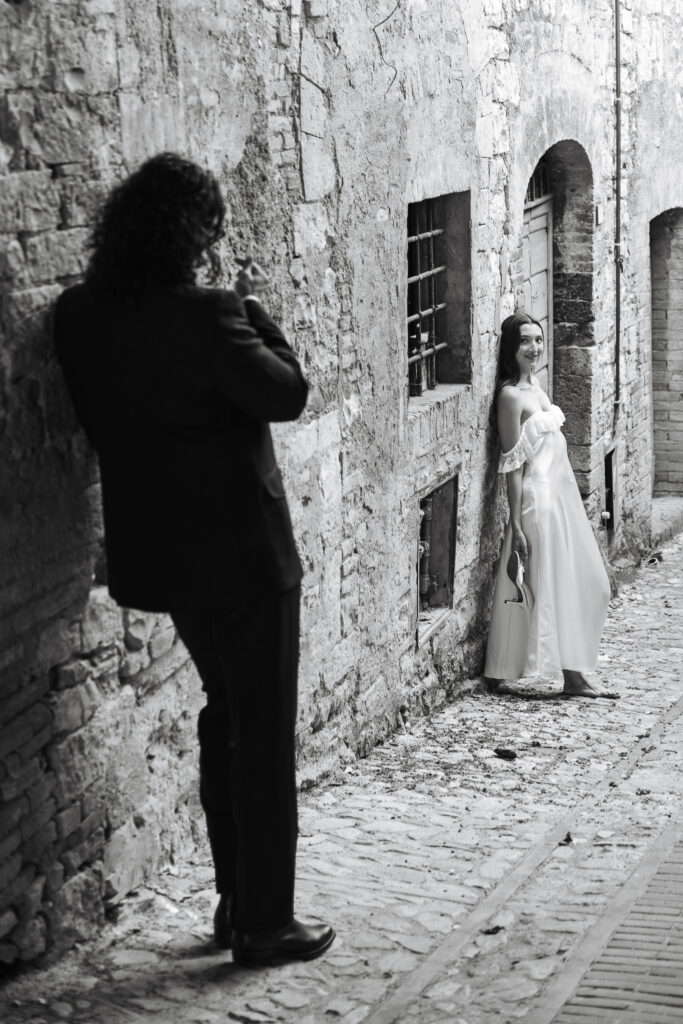 Bride smiling at the groom in a narrow stone street during an intimate black and white elopement session in Spello, Umbria.