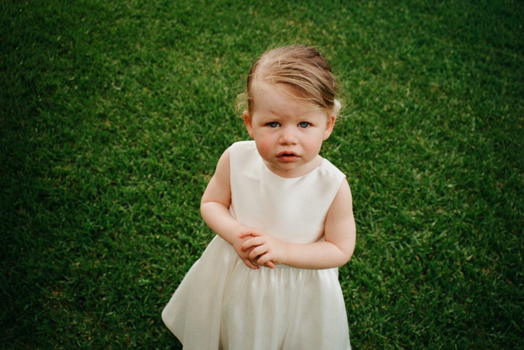 Child in a white dress during an intimate family wedding in Cefalù Sicily