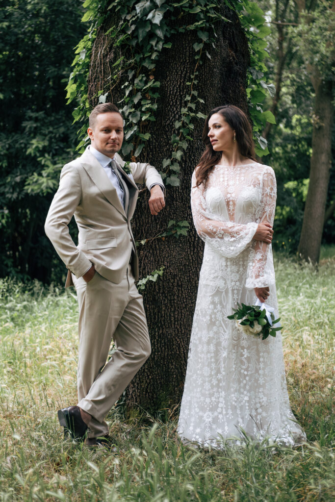 Bride and groom posing beside a large tree in Villa Borghese during their wedding photoshoot in Rome.