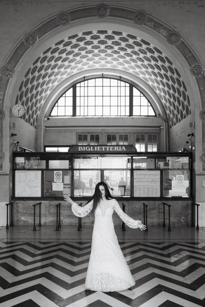Bride standing inside a historic Roman ticket hall during a black and white wedding photoshoot in Rome.