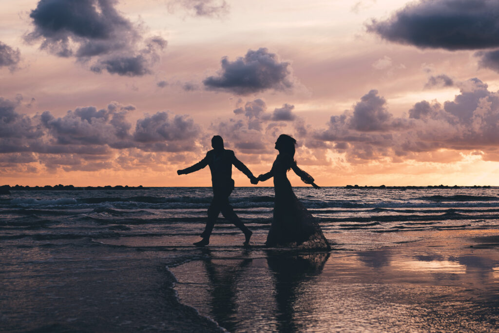 Bride and groom walking hand in hand at sunset during their Anzio beach wedding photoshoot near Rome.