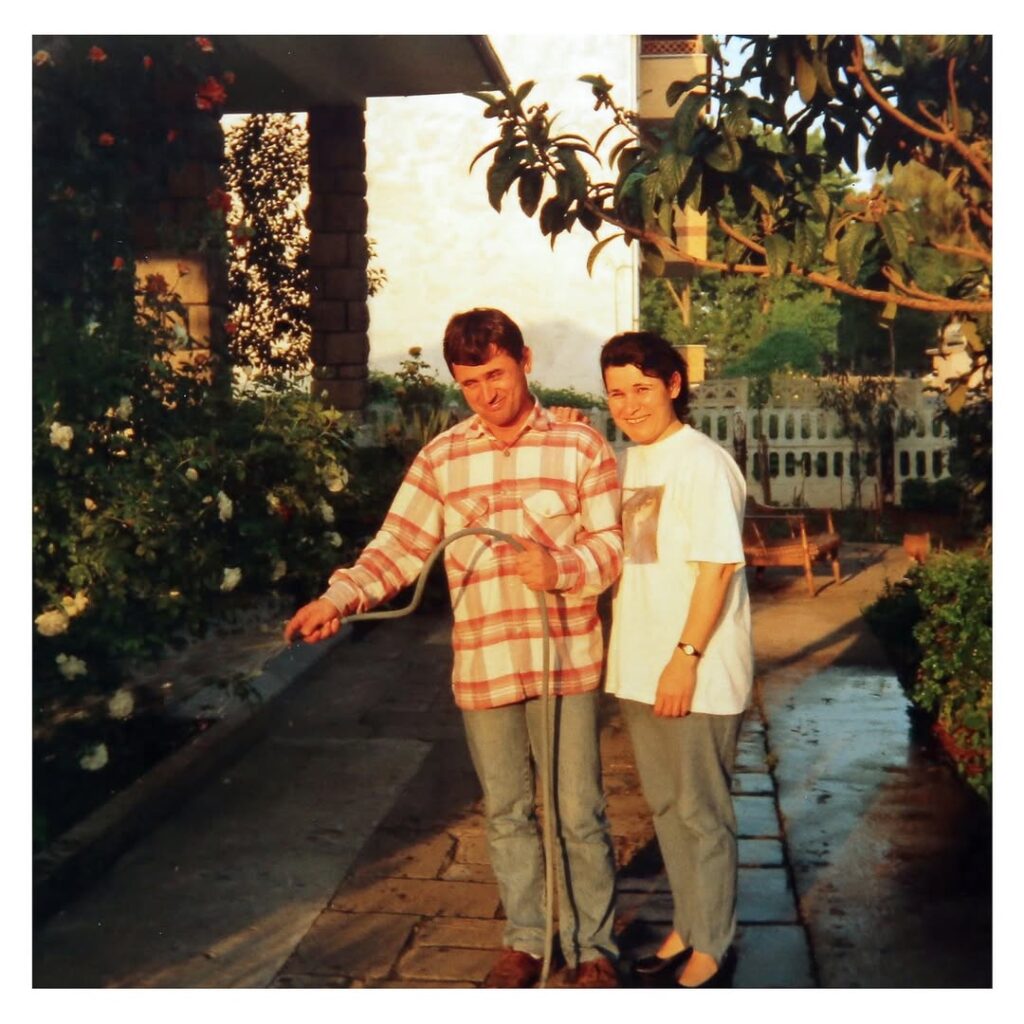 Gökhan Kutluer’s parents standing together in their garden in 1995, photographed by Gökhan at age nine in warm evening light.