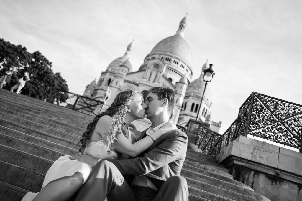 Kaylyn e Rynhardt si baciano sui gradini del Sacré Coeur durante il loro servizio fotografico di coppia a Parigi.