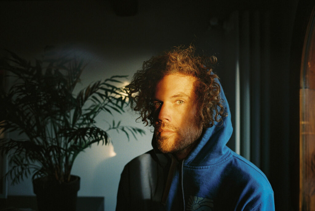 35mm film portrait of a man in a blue hoodie illuminated by warm sunlight indoors
