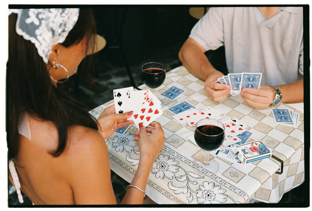 Aditi and her fiancé playing cards over red wine during a 35mm film engagement photoshoot in Rome.