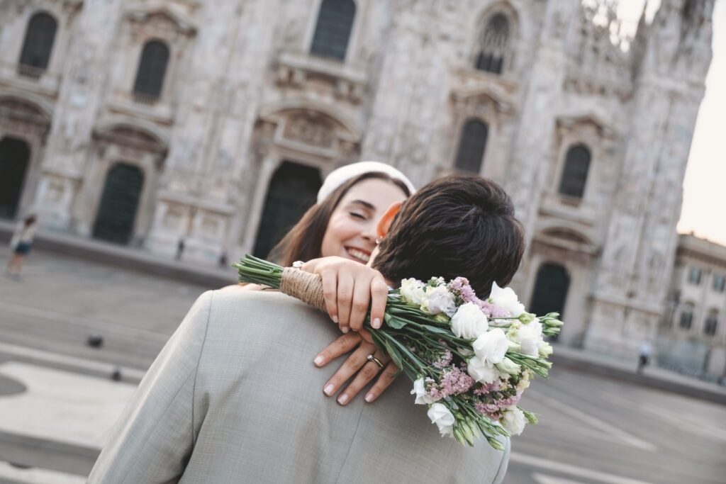 Sposa che abbraccia lo sposo con il bouquet davanti al Duomo di Milano