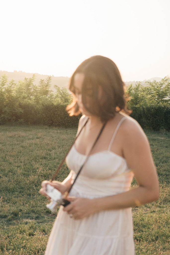 Sposa con una Leica tra le mani durante un elopement in Val d’Orcia, fotografata nella luce calda del tramonto.