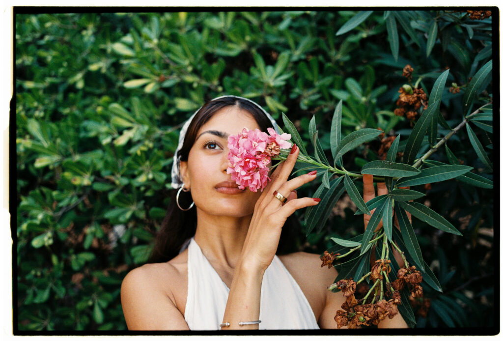 Ritratto femminile su pellicola 35mm con fiori rosa e vegetazione durante un servizio fotografico a Roma.