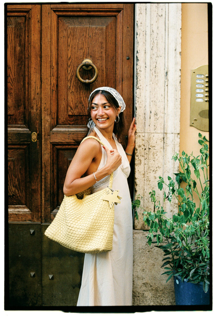 Aditi sorridente davanti a un portone romano durante un servizio fotografico di coppia su pellicola 35mm.