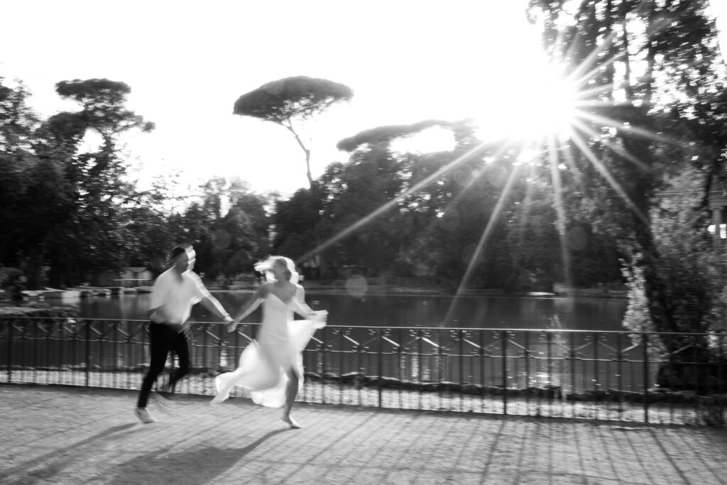 Honeymoon couple running beside the lake in Villa Borghese during a black and white Rome photography session.