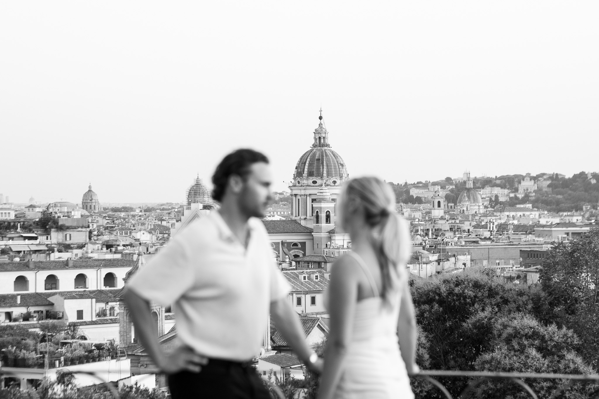 Black and white photograph of a honeymoon couple overlooking the rooftops and church domes of Rome.
