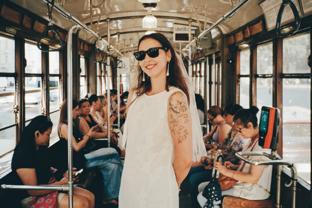Sposa con abito bianco e occhiali da sole all'interno di un tram storico di Milano
