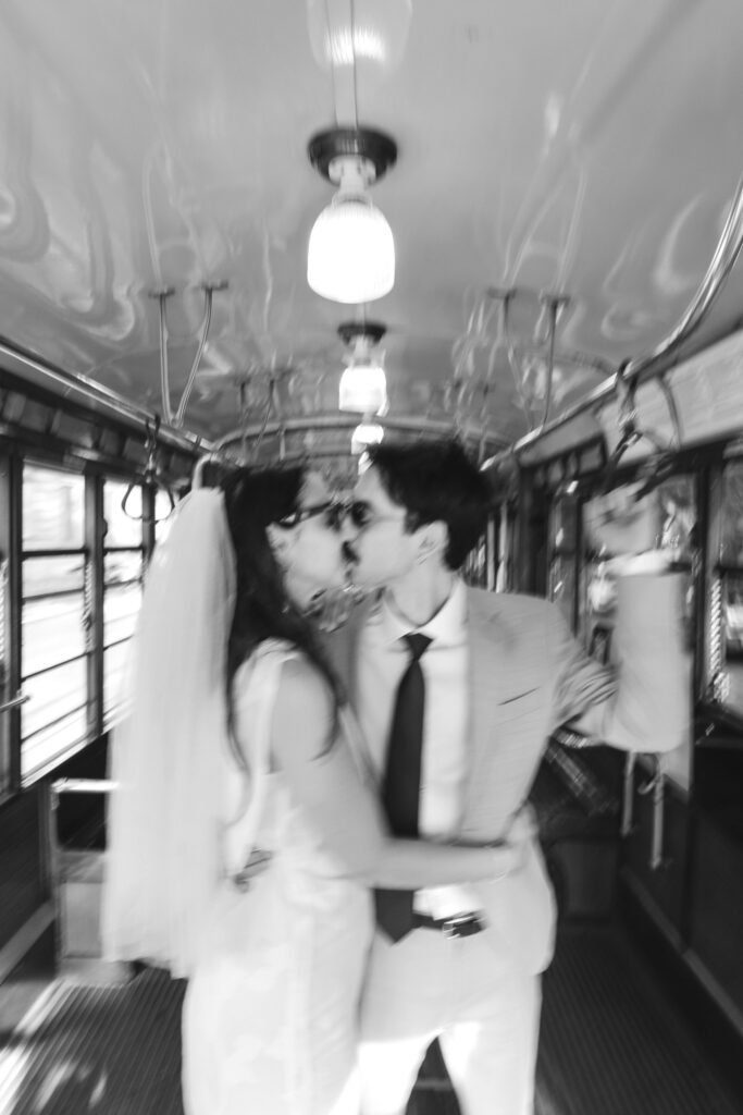 Bride and groom kissing inside a historic Milan tram in a motion blurred photograph
