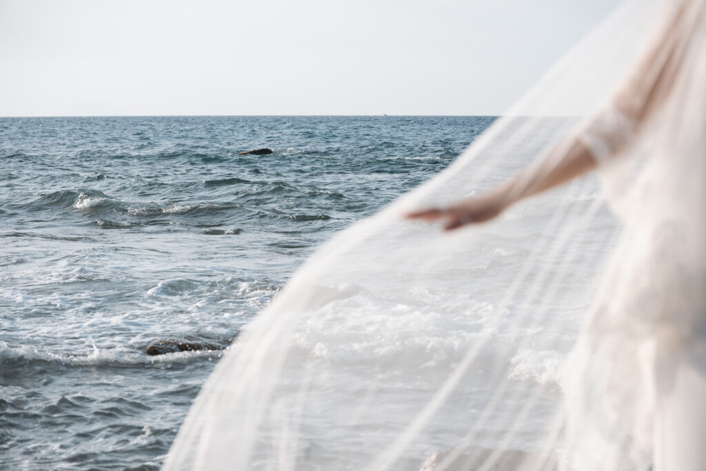 Bride’s translucent wedding veil moving above the Mediterranean Sea in Sicily, photographed by Sicily wedding photographer Gökhan Kutluer.